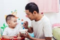 Father acting Mom feeding his son baby 1 year old on chair Royalty Free Stock Photo