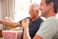 Father With Adult Son Eating Popcorn Watching Movie On Sofa At Home Together Royalty Free Stock Photo