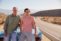 Father and adult son on road trip leaning against their car Royalty Free Stock Photo