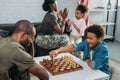 Father in army uniform playing chess with his son while mother and daughter