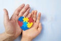 Father and autistic son hands holding jigsaw puzzle heart shape. Autism spectrum disorder family support concept. World Royalty Free Stock Photo