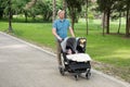 Father with kids in double stroller in a park.  Man pushing twins stroller, pram Royalty Free Stock Photo