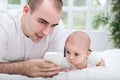 Father and baby child using smartphone and lying on bed Royalty Free Stock Photo