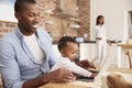 Father And Baby Daughter Use Laptop As Mother Prepares Meal Royalty Free Stock Photo