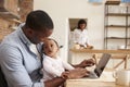 Father And Baby Daughter Use Laptop As Mother Prepares Meal Royalty Free Stock Photo