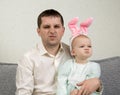 Father and baby have funny noses and bunny ears on the baby`s head