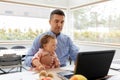 Father with baby working on laptop at home office Royalty Free Stock Photo