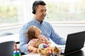 Father with baby working on laptop at home office Royalty Free Stock Photo