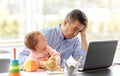 Father with baby working on laptop at home office Royalty Free Stock Photo