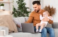 Father With Baby Working On Laptop Reading Bills At Home Royalty Free Stock Photo