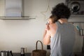 Father, back view, holding newborn while cooking in kitchen