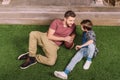 Father with ball and little son laying on the grass at backyard Royalty Free Stock Photo