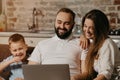 Father with beard is working remotely on a laptop near his son and wife at home Royalty Free Stock Photo