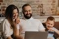 Father with beard is working remotely on a laptop near his son and wife at home Royalty Free Stock Photo