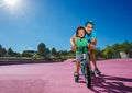 Father with blue hair help little boy learn riding a bicycle