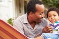 Father bonding with young son sitting in a hammock