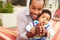 Father bonding with young son sitting in a hammock