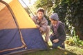 Father, boy and preparing tent for camping outdoor in nature on vacation while bonding in summer sunset. Dad, child and