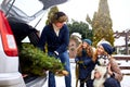 Father brought christmas tree in large trunk of SUV car. Daughter, mother and dog meet dad happily help him with