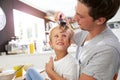 Father Brushing Son's Hair At Breakfast Table