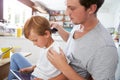 Father Brushing Son's Hair At Breakfast Table