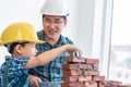 Father builder teaching his son to lay the brick wall for future career and education for family and parenting concept