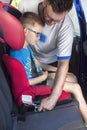 Man fastens a seat belt to a child who is sitting in a car seat in the back seat. Royalty Free Stock Photo