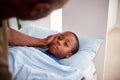 Father Caring For Sick Son Lying  Ill In Bed At Home Royalty Free Stock Photo