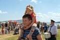 Father carries daughter on his shoulders during the music and ethnic festival Karatag on the background of people. Royalty Free Stock Photo