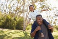 Father Carrying Son On Shoulders As They Walk In Park Royalty Free Stock Photo