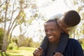 Father Carrying Son On Shoulders As They Walk In Park Royalty Free Stock Photo