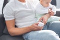 father in casual clothes sitting on couch and putting socks