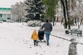 Father with child and baby walking with stroller in winter snow park. Happy family, connections on weekend Royalty Free Stock Photo