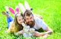 Father and child with cute bunny ears lying at meadow. Family feast concept. Dad and girl play in spring garden on sunny Royalty Free Stock Photo