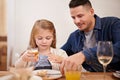 Father, child and help with meal in home, food and healthy lunch for nutrition at dining table. Daddy, girl and teaching Royalty Free Stock Photo
