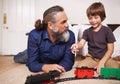 Father, child and play with toy train and joy in home or house with fun. Mature man, kid and happiness with smile, youth Royalty Free Stock Photo