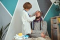 Father and child playing clinic and doctor, little boy dentist in medical gown with stethoscope treats dad Royalty Free Stock Photo