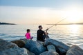 Father with children on a fishing trip by the sea. A boy and a girl with their father have fun fishing on the beach or by the sea.