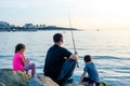 Father with children on a fishing trip by the sea. A boy and a girl with their father have fun fishing on the beach or by the sea.