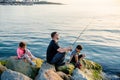 Father with children on a fishing trip by the sea. A boy and a girl with their father have fun fishing on the beach or by the sea.