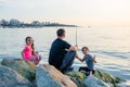 Father with children on a fishing trip by the sea. A boy and a girl with their father have fun fishing on the beach or by the sea.