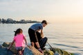 Father with children on a fishing trip by the sea. A boy and a girl with their father have fun fishing on the beach or by the sea.