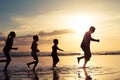 Father and children playing on the beach at the sunset time. Royalty Free Stock Photo