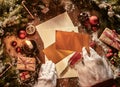 Father Christmas writing a letter to celebrate Xmas in an overhead view of his hands holding envelopes above vintage paper and a