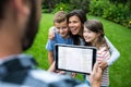 Father clicking picture of family from digital tablet in park