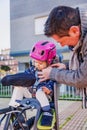 Father closing helmet to her daughter sitting in bike seat Royalty Free Stock Photo