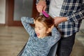 Father combing, brushing his daughter& x27;s hair at home, child making faces about hair pulling Royalty Free Stock Photo