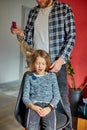 Father combing, brushing his daughter& x27;s hair at home, child making faces about hair pulling Royalty Free Stock Photo