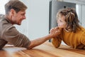 Father competing in arm wrestling with teen son, family spending time together.