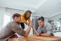 Father competing in arm wrestling with teen son, family spending time together.